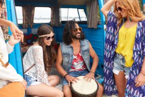 happy hippie friends playing music in minivan